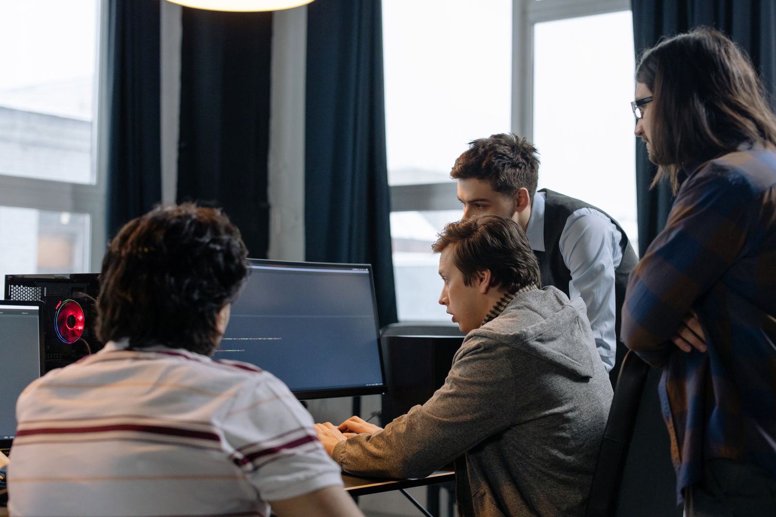 A small engineering team discussing implementation at a shared workstation.